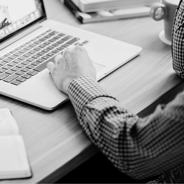 Man's arm resting on a laptop on a desk