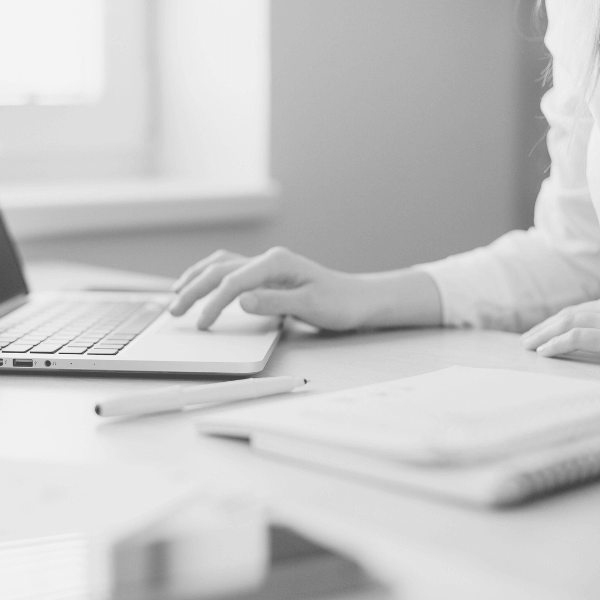 woman's arm and hand typing on a laptop at a desk