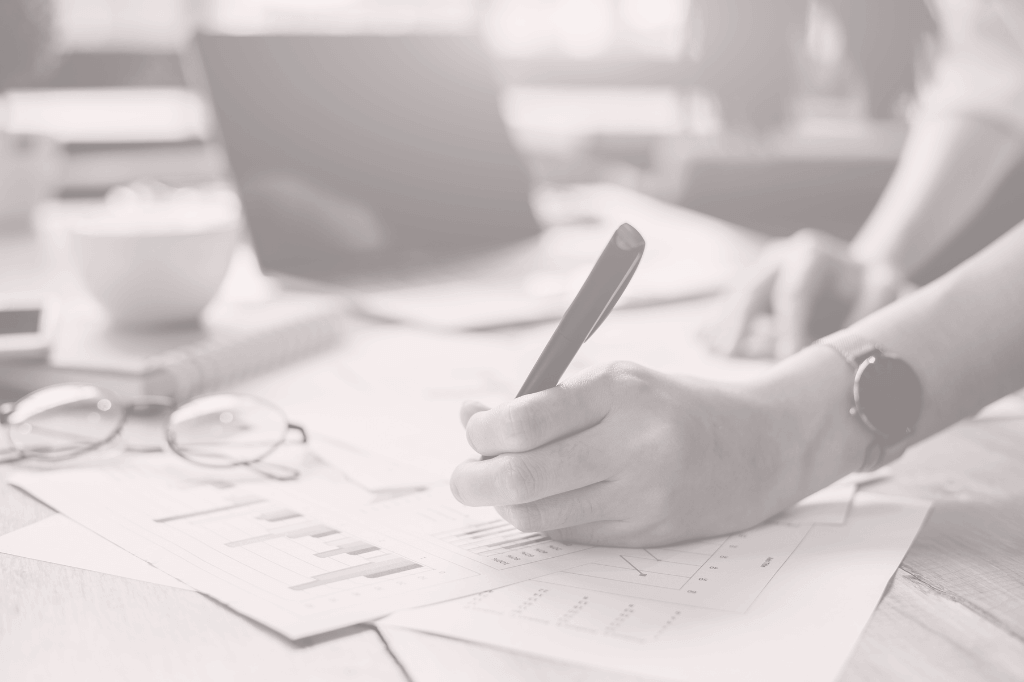 Paperwork on a desk with a woman's hand making notes with a pen